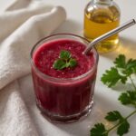 Glass of vibrant red juice with parsley garnish and metal straw part of the best detox juice cleanse