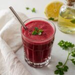 A vibrant glass of beetroot detox juice garnished with fresh parsley and served with a stainless steel straw—an elegant representation of the best way to detox alcohol naturally.