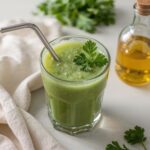 Green detox juice in a glass with a metal straw and parsley garnish—ideal for heavy metal detox naturally using fresh herbs and cold pressed ingredients.